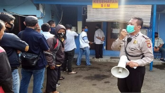 Petugas kepolisian menyosialisasikan penerapan protokol kesehatan kepada pemohon layanan SIM yang mengantre di Satpas SIM Daan Mogot, Jakarta Barat, Selasa (23/6/2020) | ANTARA