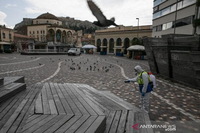 Seorang petugas mendisinfeksi alun-alun Kota Athena, Yunani, Senin (23/3/2020) | ANTARA FOTO
