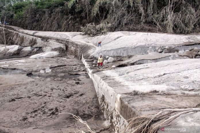 Warga berjalan di samping jalur lahar panas Gunung Semeru di kawasan Pronojiwo, Lumajang, Jawa Timur, Rabu (2/12/2020). Gunung Semeru mengalami erupsi yang menyebabkan awan panas letusan meluncur ke arah Curah Besuk Kobokan sepanjang 11 kilometer dengan durasi kemunculan awan panas selama tiga jam serta status level II atau waspada. ANTARA FOTO | UMARUL FARUQ
