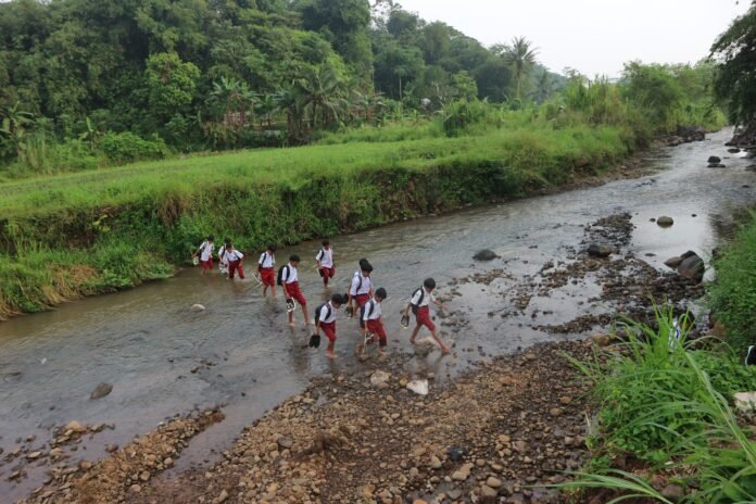 Perjuangan pagi para pelajar Bogor melintasi Sungai Cihideung demi meraih pendidikan yang lebih baik. Foto: Harnas.id/ Rangga Firmansyah