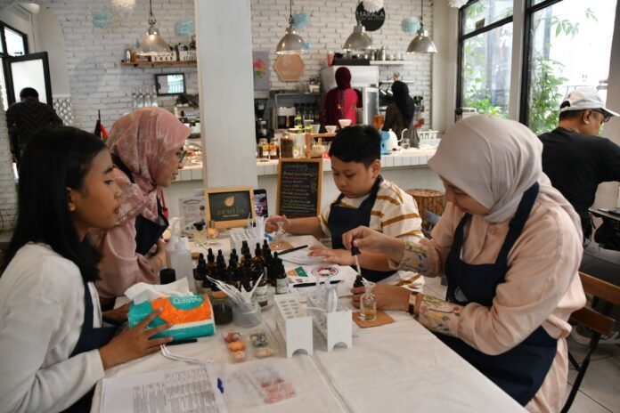 Seorang anak dan ibunya meracik parfum bebas alkohol dalam workshop Zentia di Maraca Cafe, Bogor, Sabtu (27/6/2025). Kegiatan ini mengedukasi penggunaan produk perawatan diri yang aman untuk anak. Foto: Harnas.id