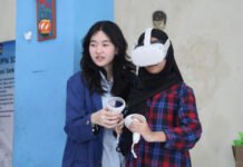 ITS Uji Coba RRekon VR, Edukasi Rekonstruksi Bencana Kini Masuk Ruang Kelas Mahasiswi ITS (kiri) ketika sedang memandu salah satu siswi SMPN 32 Surabaya saat mencoba menggunakan RRekon VR. Foto: Humas ITS