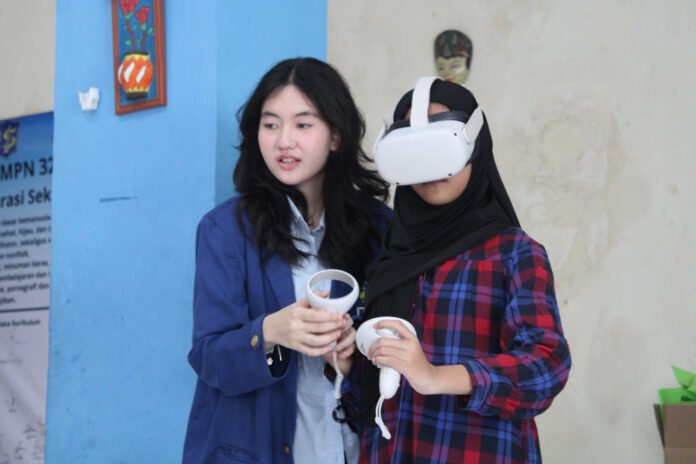 Mahasiswi ITS (kiri) ketika sedang memandu salah satu siswi SMPN 32 Surabaya saat mencoba menggunakan RRekon VR. Foto: Humas ITS