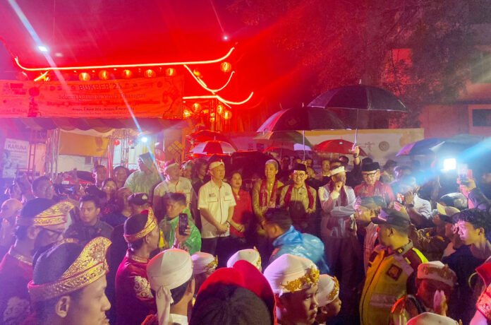 Pengunjung mengenakan jas hujan saat menyaksikan parade BSF Cap Go Meh 2026 di Suryakencana, Bogor. Foto: Pemkot Bogor