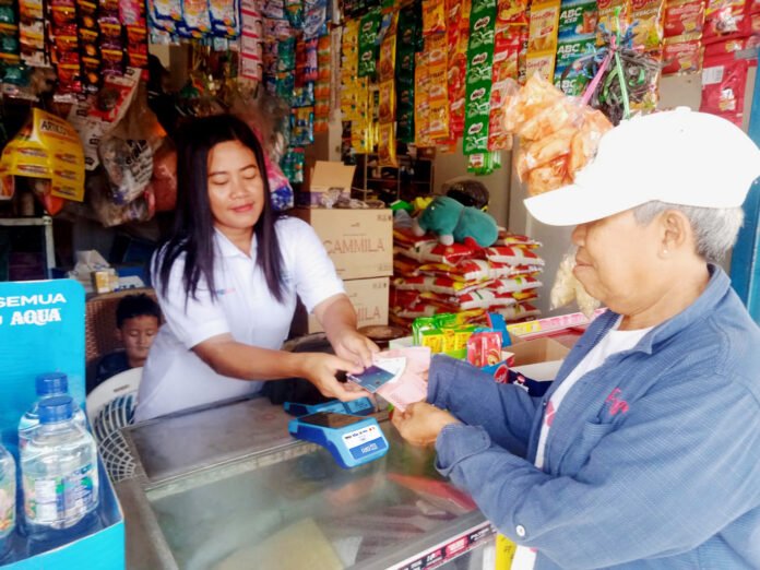Agen BRILink perempuan di Palembang melayani transaksi keuangan warga di kios usahanya. Foto: Humas BRI