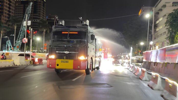 Personel Brimob Polda Metro Jaya menyemprot ruas jalan sebagai antisipasi endapan abu vulkanik